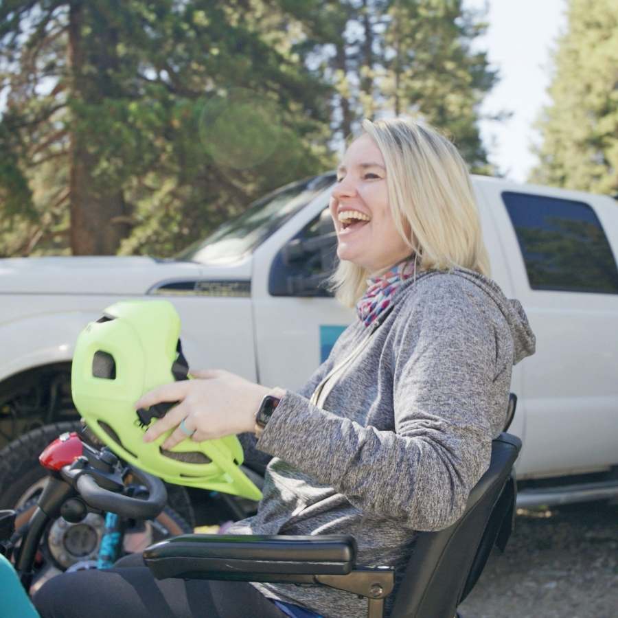 Janelle laughing while putting on her biking helmet.