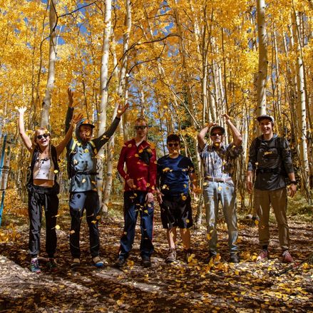 Photo of people throwing leaves in the air.