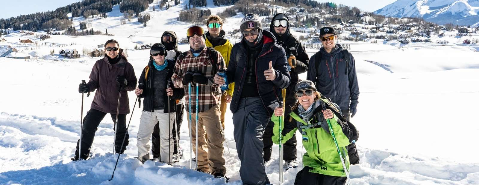 A group of showshoers posing for a photo in front of a mountain